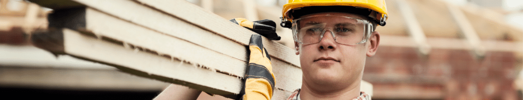 Construction worker with hard hat carrying lumber